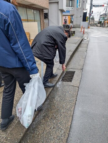 ゴミ拾い中の様子（側溝の下のゴミを拾っている様子）