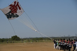 写真：「新風」と書かれた大凧が大空を舞う様子