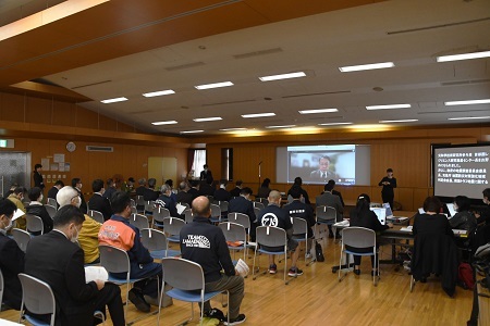 写真：キックオフ防災講演会にて。講師の説明を参加者が聞いている。