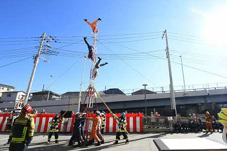 棒や紐を使って数人で梯子を支えている。その梯子に3人が乗り華麗な技を披露している。