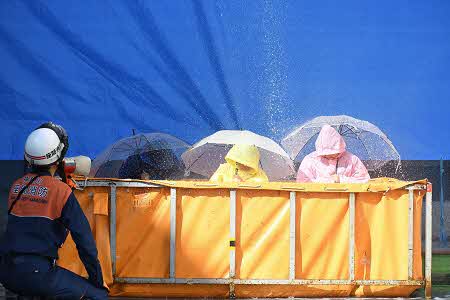 ゲリラ豪雨を体験している参加者3人が傘をさしている。