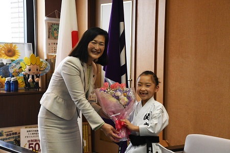 写真：市長から花束を受け取る鰺坂さん