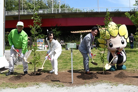 写真：緑化祭り実行委員会委員長大塚さん、佐藤市長、荻原市議会議長、市マスコットキャラクターざまりんが植樹している