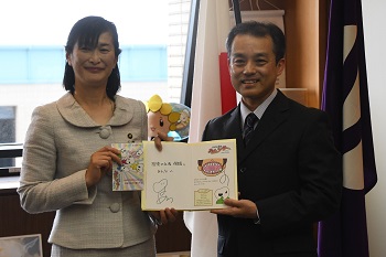 写真：小林さんと市長が寄贈する絵本を持っている