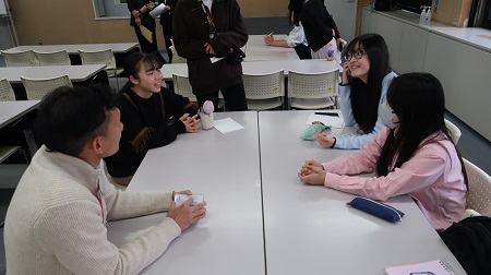 外国語指導助手（ALT）と3人の国際親善大使の女性が笑顔で会話をしている様子