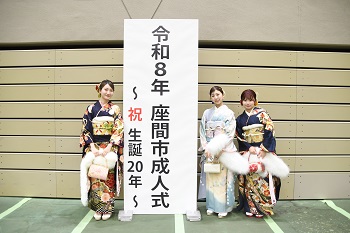 写真：令和8年座間市成人式～祝生誕20年～と書かれた立て看板で記念撮影をする振袖姿の女性3人