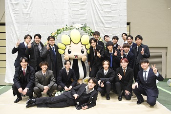 写真：スーツを着た男性が大人数で市マスコットキャラクターざまりんと記念撮影をしている様子