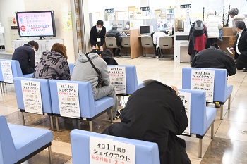 写真:職員の指示に従って姿勢を低くして頭を守る来庁者たち