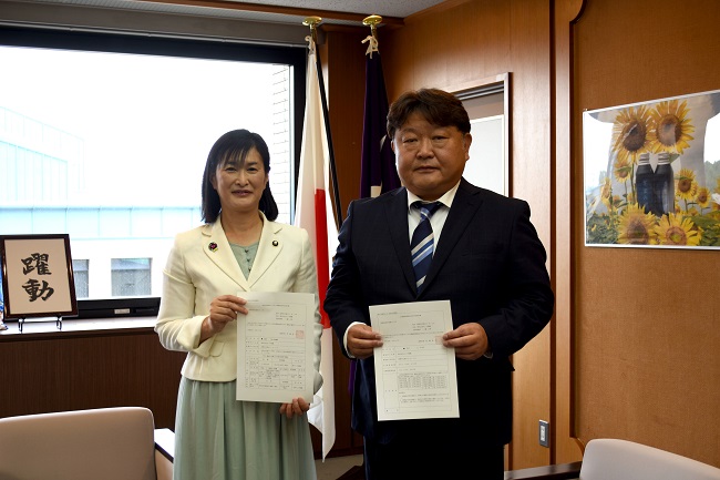 写真:(左から)市長、いちのせ まさかずさんが互いに交付決定通知書を持って並ぶ様子