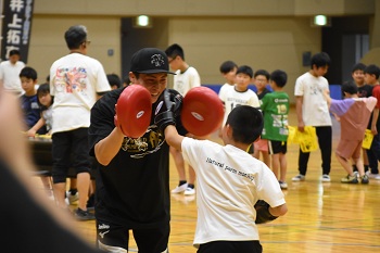 写真:ミット打ち体験に参加するいのうえなおや選手