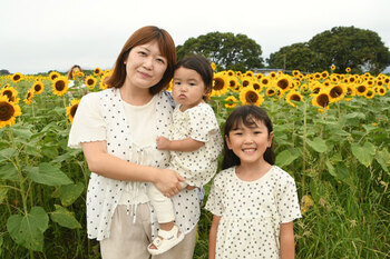 写真：四ツ谷会場のヒマワリを背景に親子連れが立っている様子
