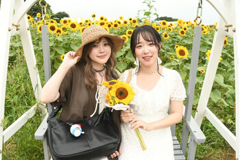 写真：四ツ谷会場のヒマワリを背景に、切り花を持った来場者がブランコに乗っている様子