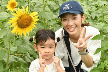 写真：座間会場のヒマワリを背景に親子連れがピースをしている様子