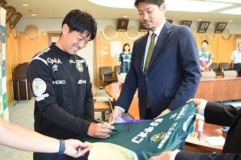 写真:むとう選手がユニフォームのレプリカにサインをする様子